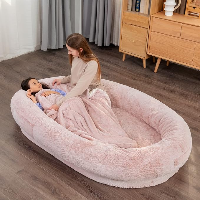 pink human-sized pet bed with people relaxing and cuddling dogs
