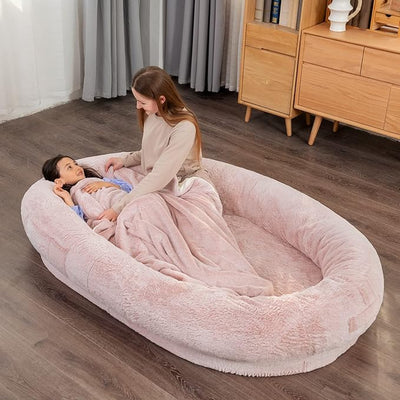 pink human-sized pet bed with people relaxing and cuddling dogs
